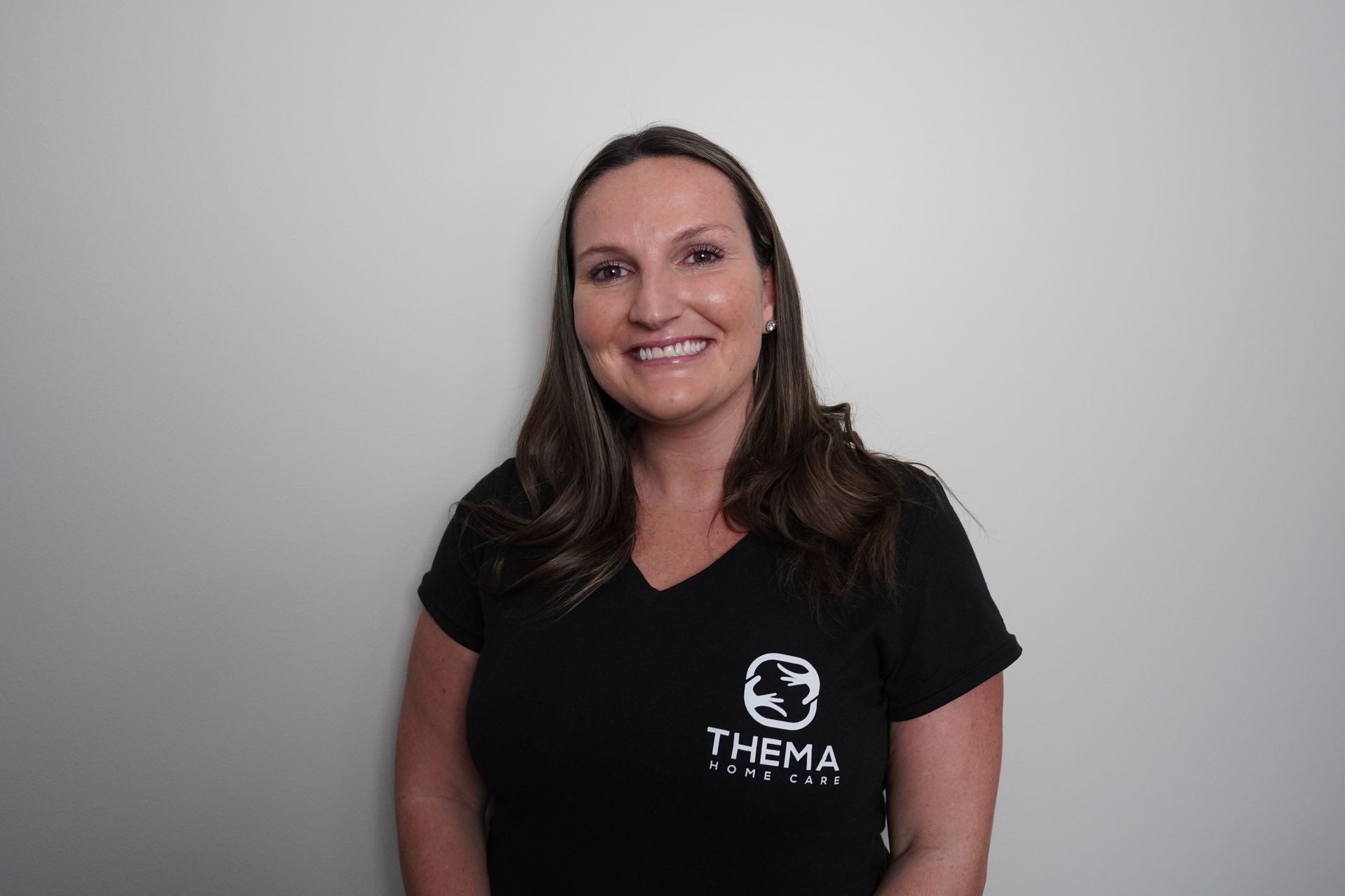 Smiling person wearing a black Thema Home Care shirt against a plain background.