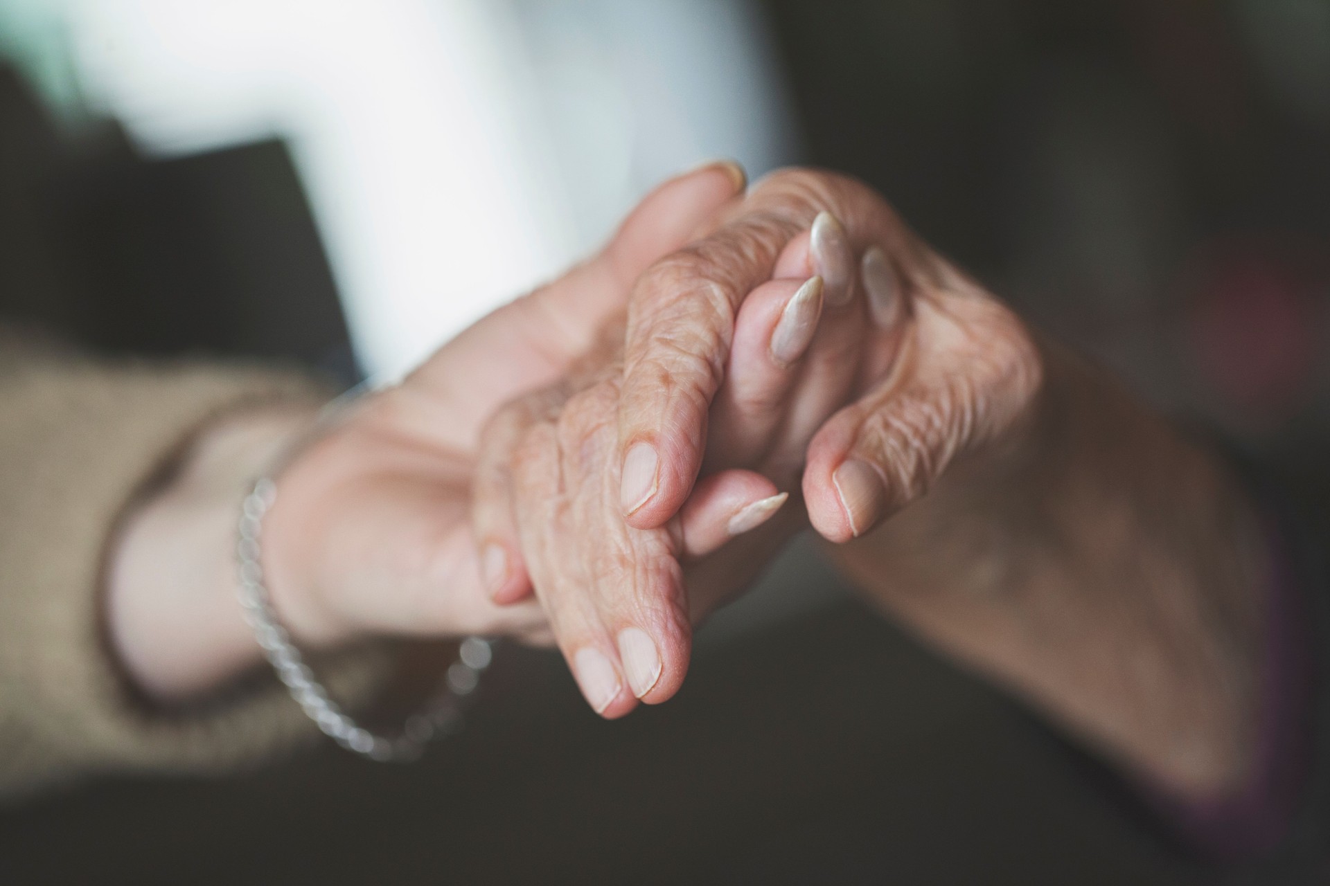 Daughter holding hand of her old mother